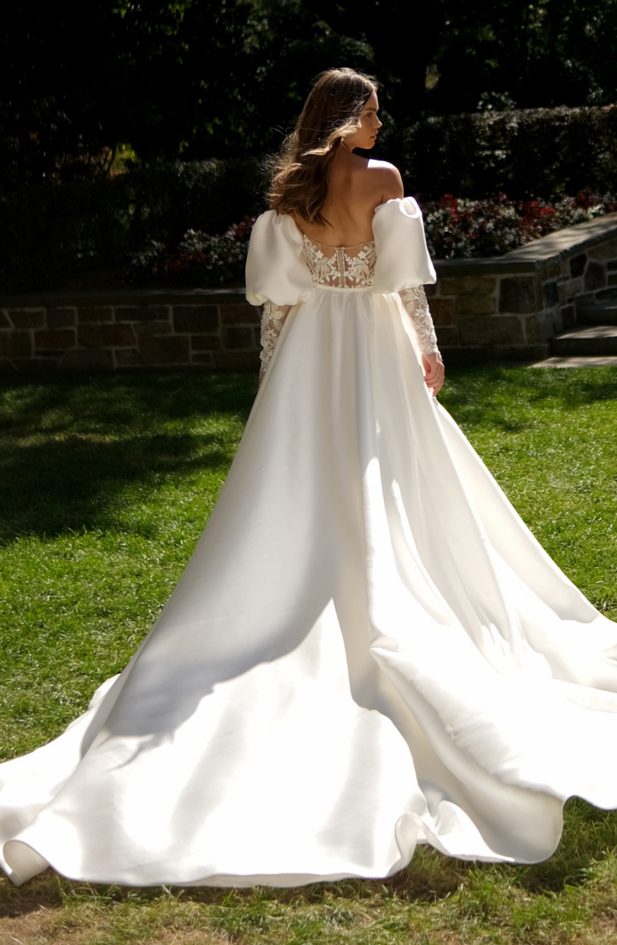model is wearing a fit and flare puff sleeve wedding dress with a bow