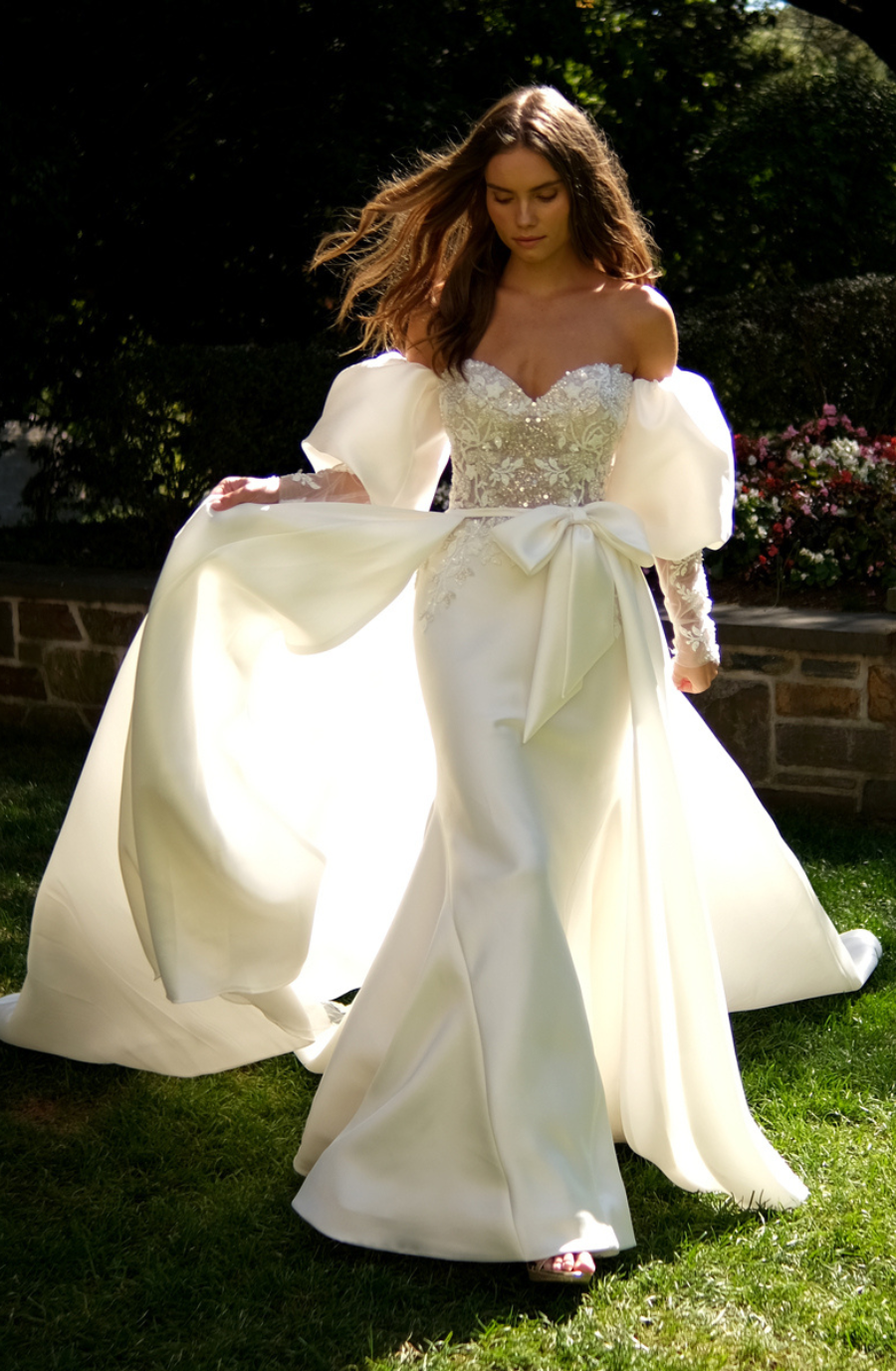 model is wearing a fit and flare puff sleeve wedding dress with a bow