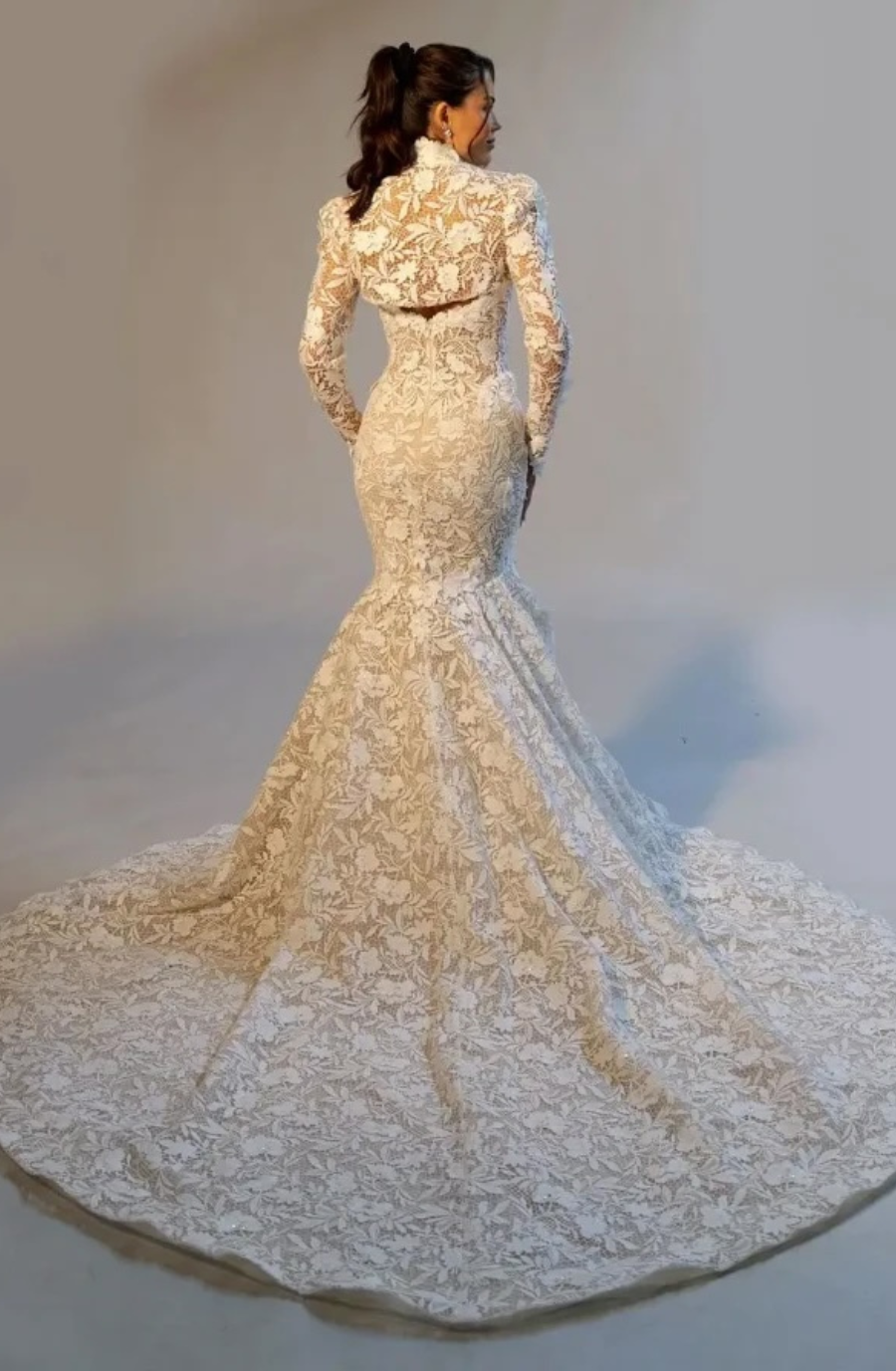 image shows the back of a lace fit and flare bridal gown with an overskirt