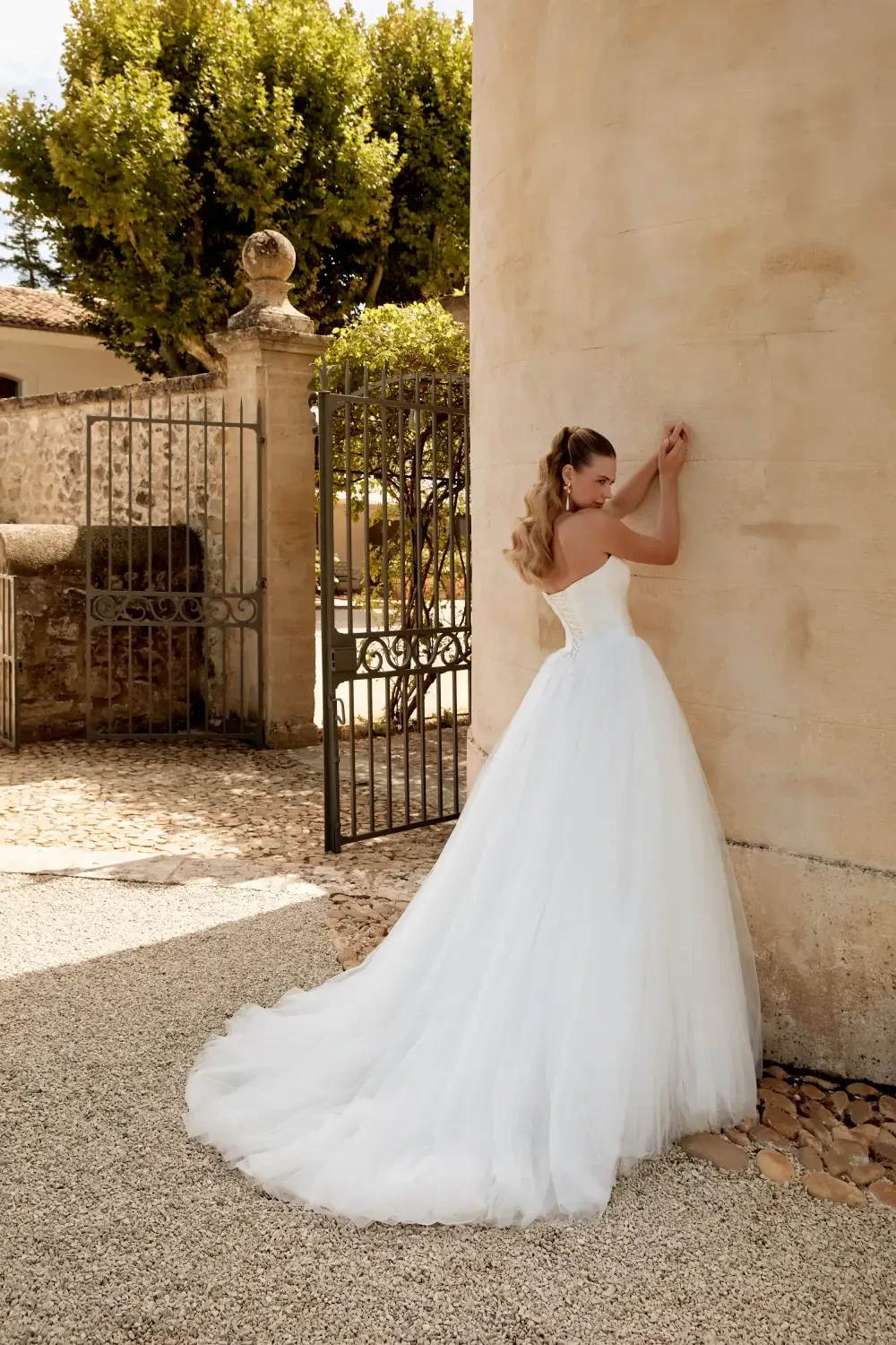 model is wearing an open back ball gown