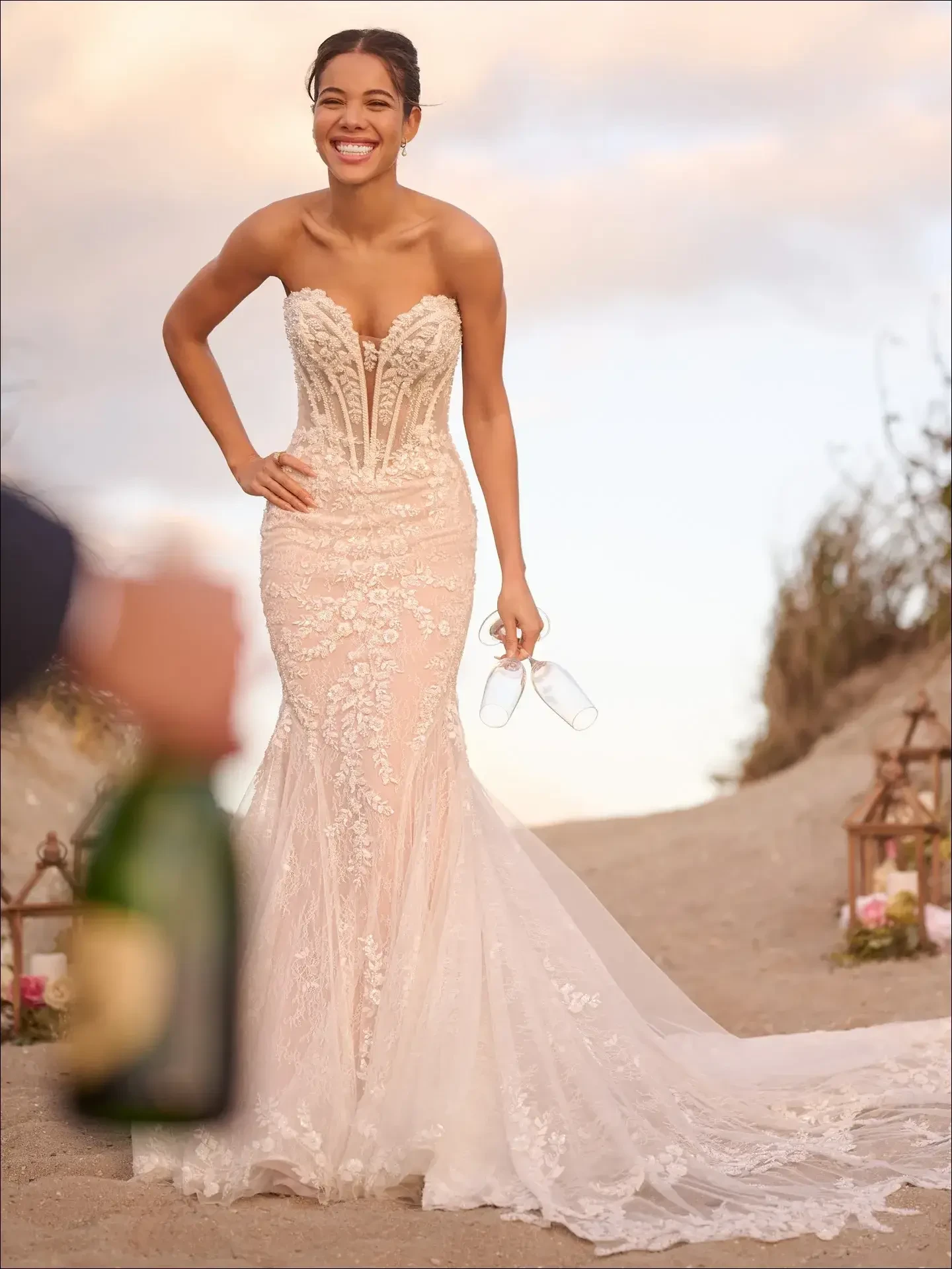 Model is wearing a strapless mermaid gown with shimmering beaded details and a dramatic, curve-hugging silhouette.