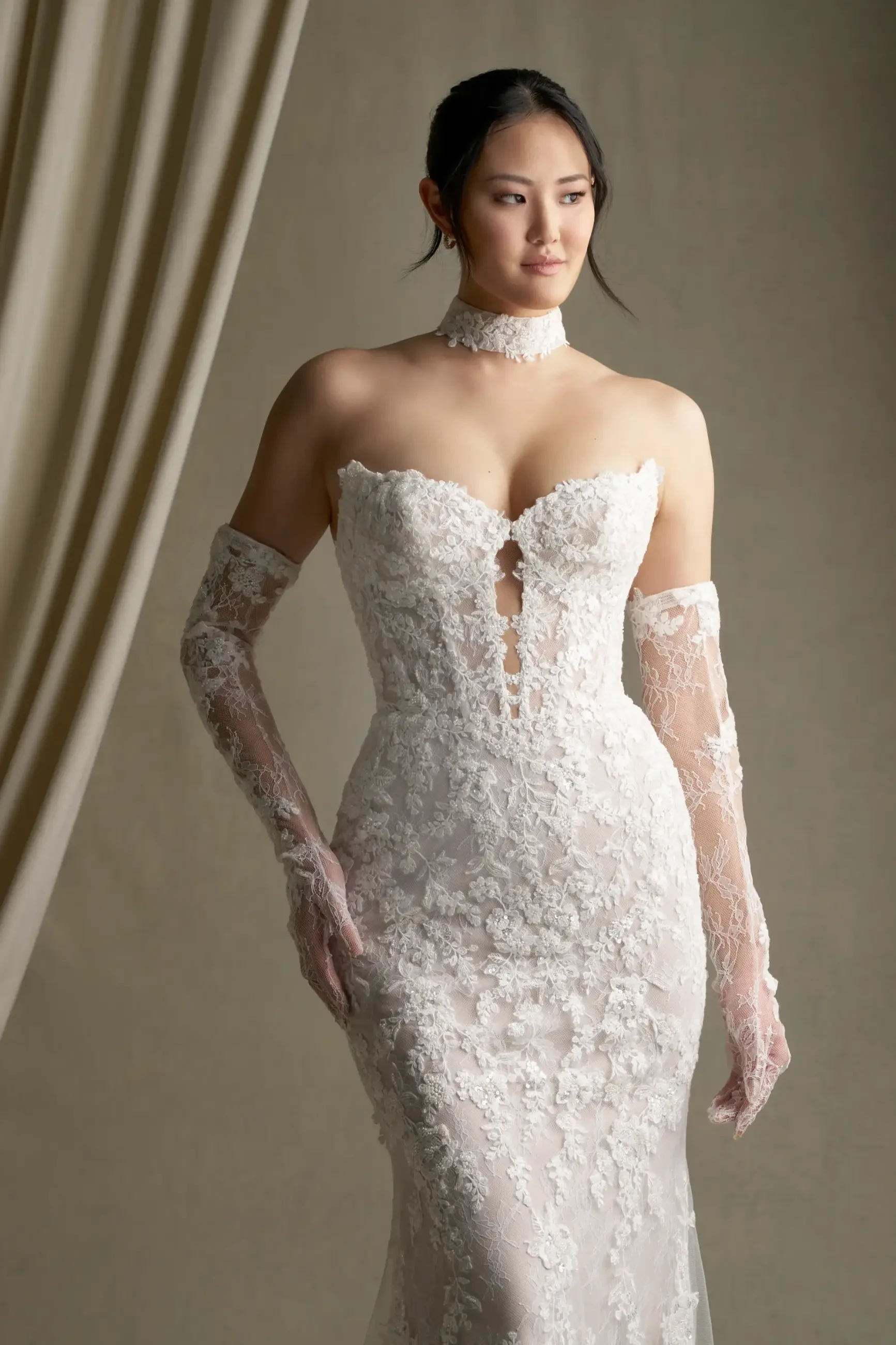 model is wearing a strapless lace fit and flare wedding dress with gauntlet sleeves