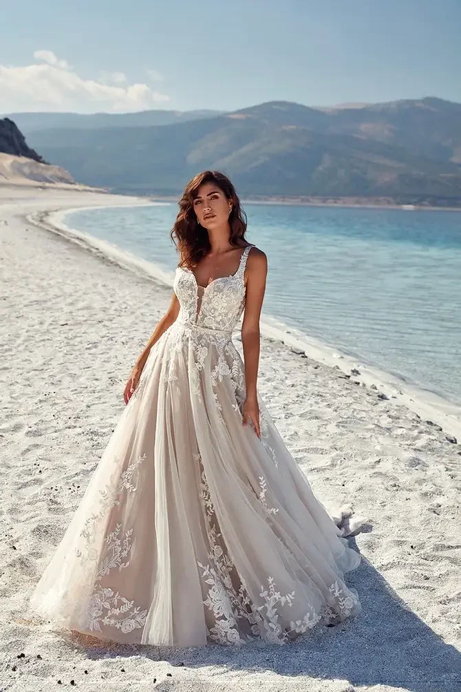 Model is wearing an ivory A-line gown with sequined lace over champagne and mocha tulle, featuring a soft, romantic shimmer.
