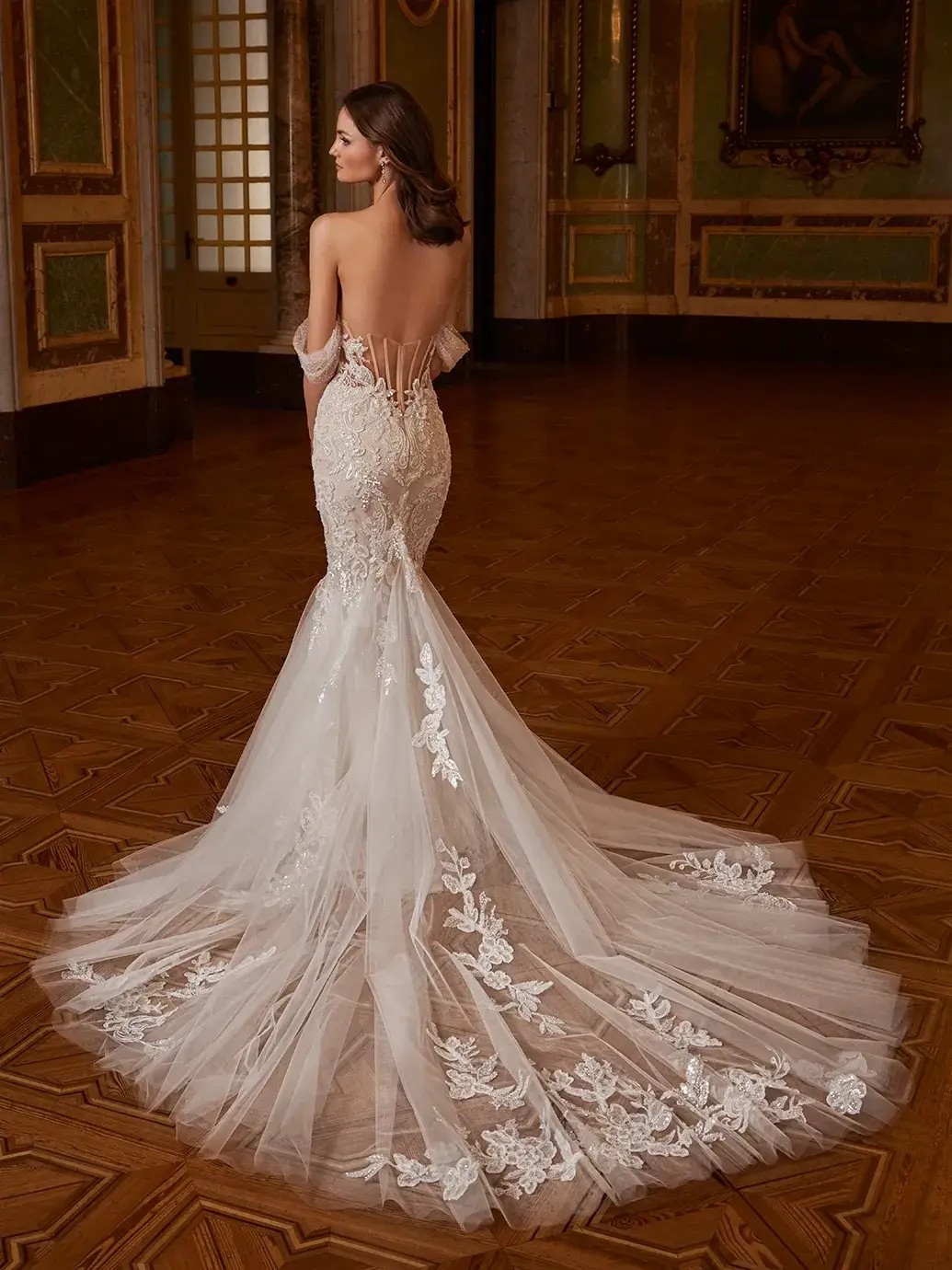 Model is wearing a wedding dress with a detachable ball gown overskirt and romantic floral embroidery
