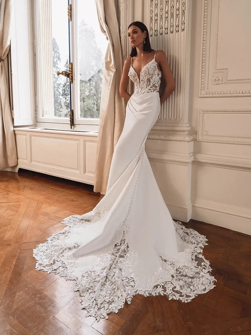 Model is wearing a mikado mermaid wedding dress with a slit and deep v neckline