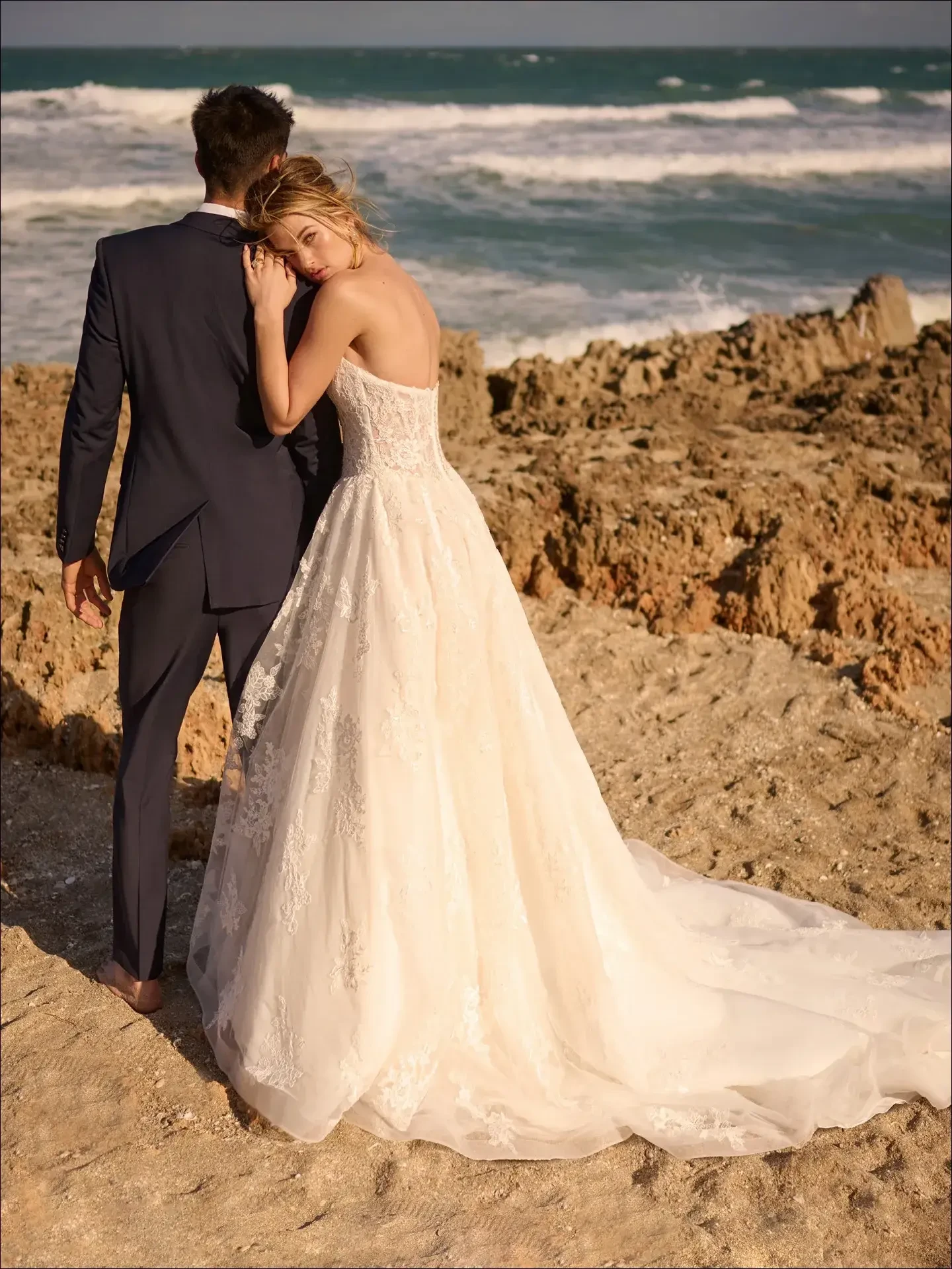 Model is wearing a classic A-line gown with lace motifs, a basque waist, and optional tulle cap sleeves 