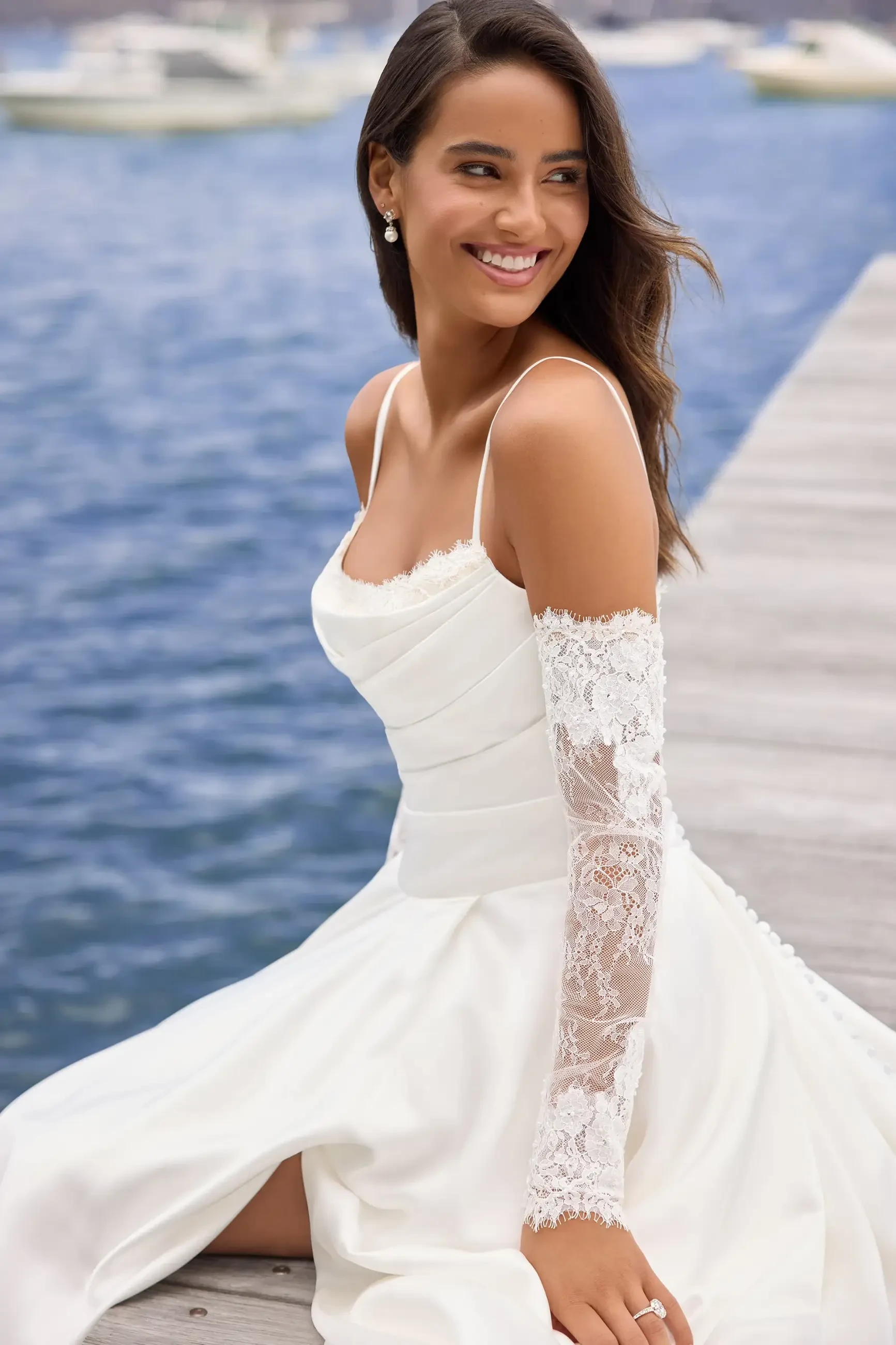 Model is wearing a luxurious satin gown with a delicately ruched bodice, off-the-shoulder lace sleeves, and spaghetti straps for a modern romantic look.
