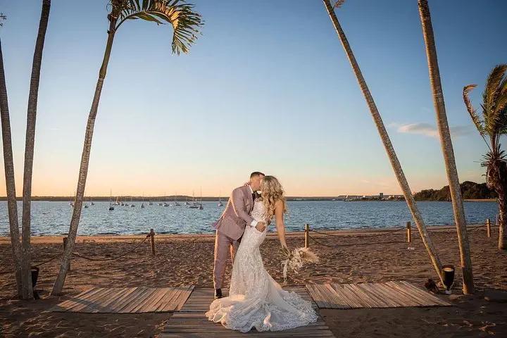 Photo of a real bride and groom kissing near the water